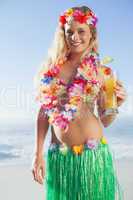 Gorgeous blonde in garland and grass skirt holding cocktail on t