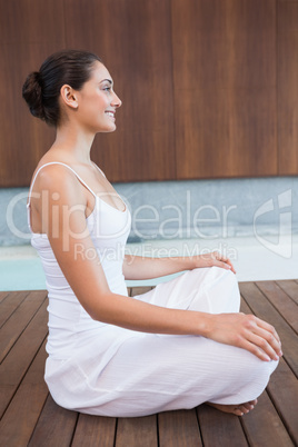 Content brunette in white sitting in lotus pose