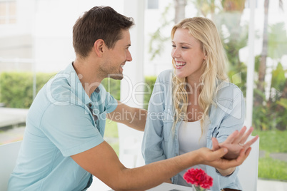 Hip young couple sitting at table smiling at each other