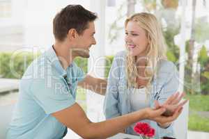 Hip young couple sitting at table smiling at each other