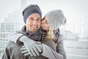 Cute couple in warm clothing hugging man smiling at camera