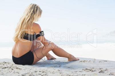 Fit blonde sitting in on the beach taking a break