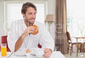 Handsome man having breakfast in his bathrobe