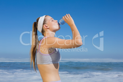 Sporty blonde drinking water on the beach