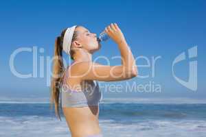 Sporty blonde drinking water on the beach