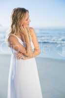 Pretty blonde standing at the beach in white sundress