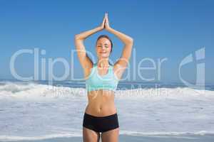 Fit woman standing on the beach with hands together