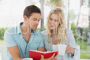 Hip young couple having coffee together reading book