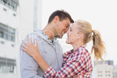 Hip young couple hugging about to kiss