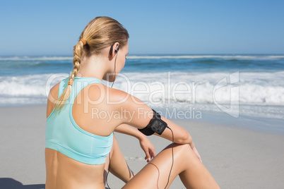 Fit woman sitting on the beach taking a break