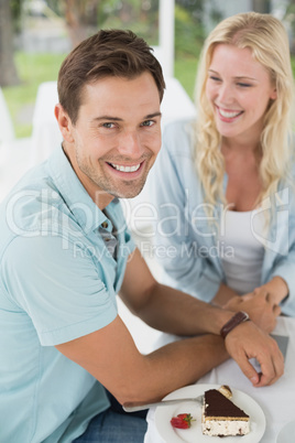 Hip young smiling couple having desert together