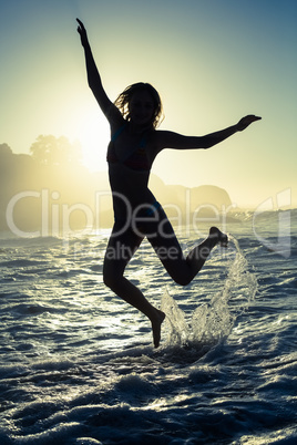 Happy blonde in the sea leaping in bikini