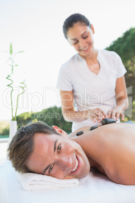 Handsome man getting a hot stone massage poolside