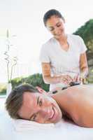 Handsome man getting a hot stone massage poolside