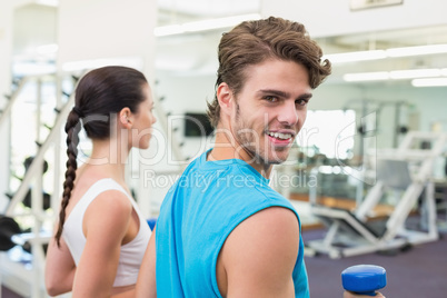 Fit couple exercising together with blue dumbbells