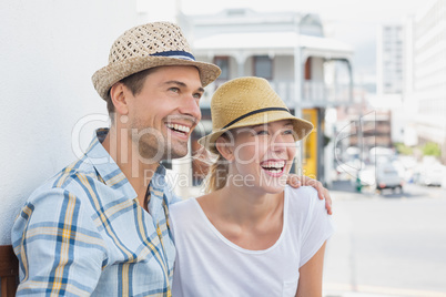 Young hip couple sitting on bench smiling