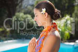 Brunette in sarong meditating by the pool