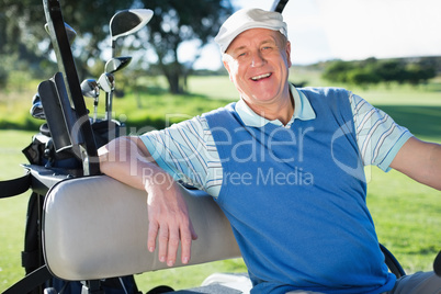 Happy golfer driving his golf buggy smiling at camera