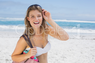 Beautiful smiling blonde on the beach holding bag