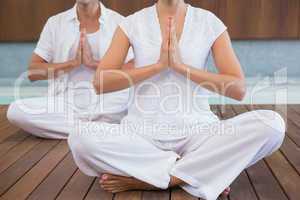 Couple in white sitting in lotus pose with hands together