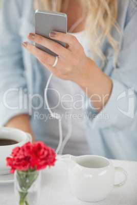 Cute blonde sending a text message in cafe