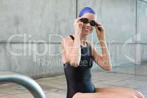 Smiling swimmer sitting at the edge of the swimming pool