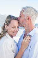 Man kissing his smiling partner on the forehead at the beach