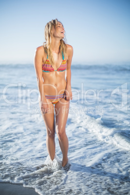 Smiling blonde standing on the beach in bikini