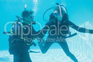 Friends on scuba training submerged in swimming pool