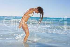 Beautiful woman in white bikini tossing wet hair