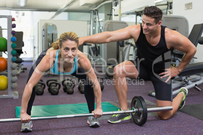 Personal trainer coaching female bodybuilder lifting barbell