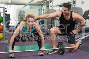 Personal trainer coaching female bodybuilder lifting barbell