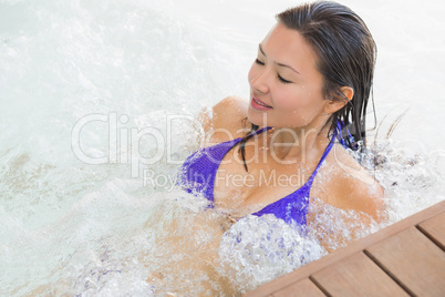 Smiling brunette in bikini relaxing in hot tub