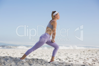 Sporty blonde on the beach stretching