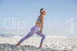 Sporty blonde on the beach stretching