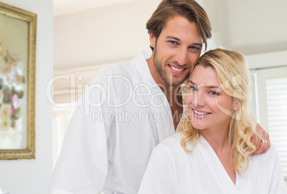 Cute couple in bathrobes smiling at camera together