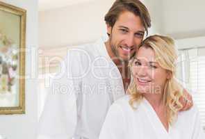 Cute couple in bathrobes smiling at camera together