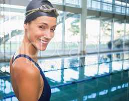 Pretty swimmer smiling at camera by the pool