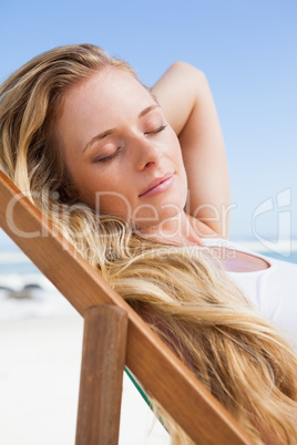 Gorgeous blonde sitting at the beach with eyes closed