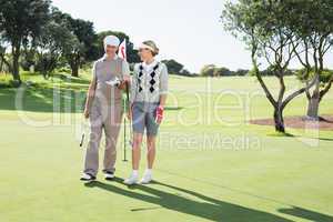 Golfing couple smiling at each other on the putting green