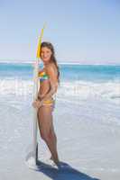 Beautiful smiling surfer girl standing on the beach with her sur