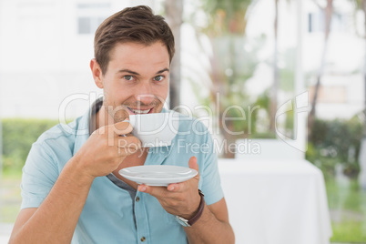 Handsome man sitting at table having coffee