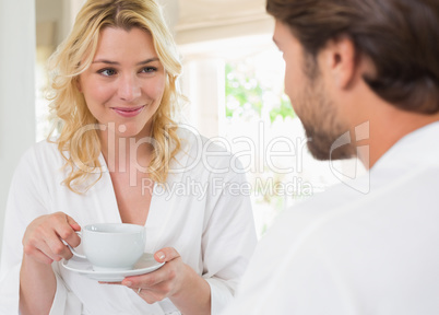 Cute couple in bathrobes having coffee together