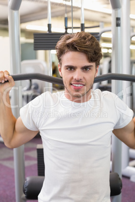 Fit man using weights machine for arms smiling at camera