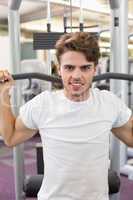 Fit man using weights machine for arms smiling at camera