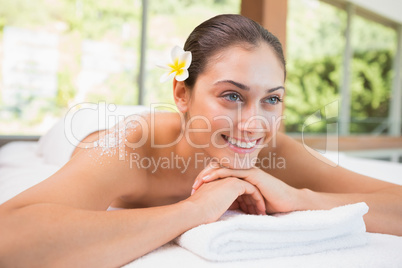 Beautiful smiling brunette lying on massage table with salt scru