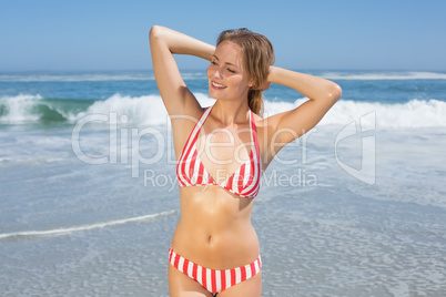 Blonde fit woman in striped bikini at beach smiling