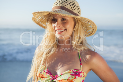 Gorgeous blonde in straw hat and bikini smiling on beach
