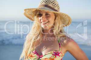 Gorgeous blonde in straw hat and bikini smiling on beach