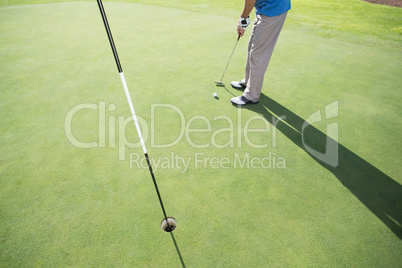 Golfer putting ball on the green